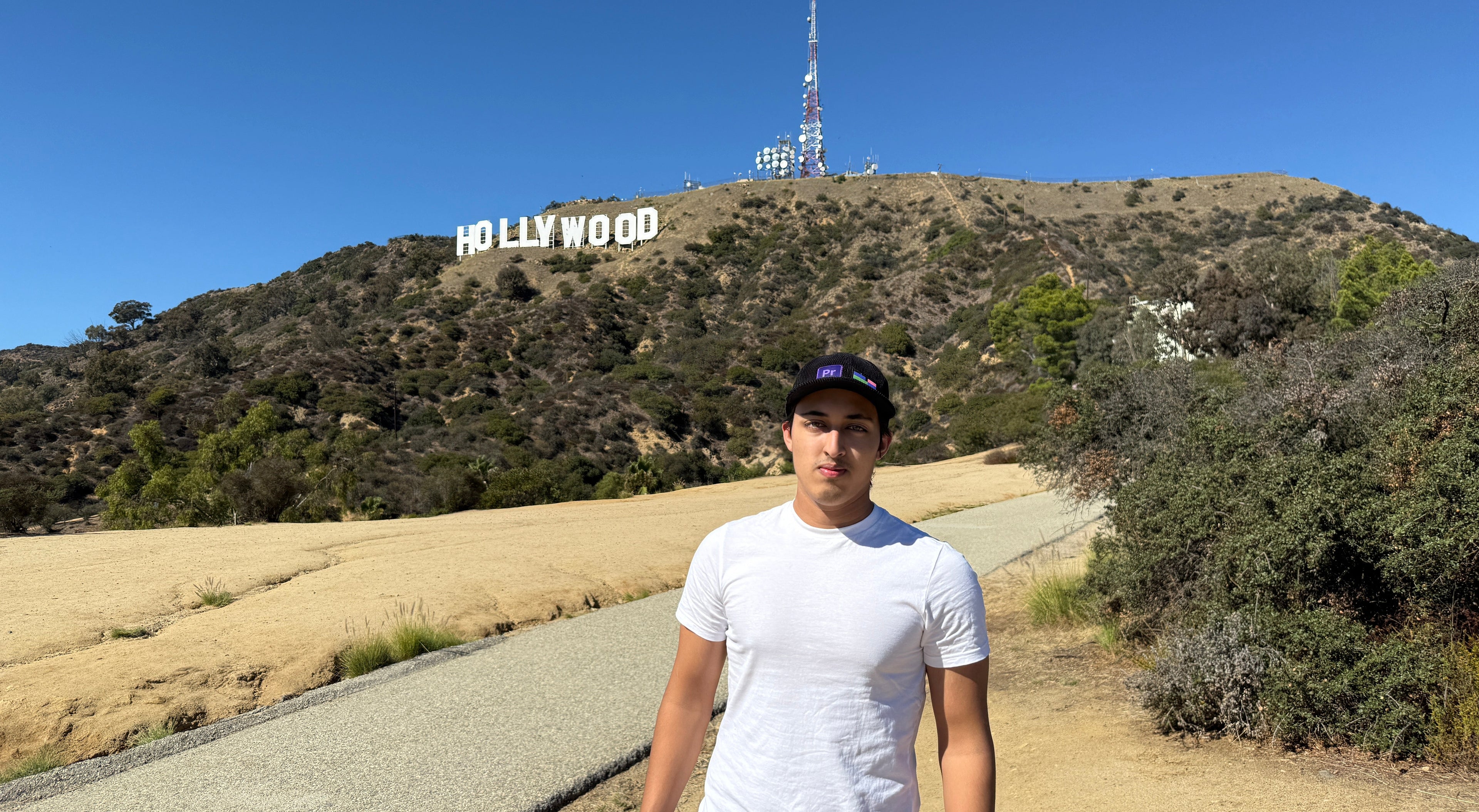 Person standing in front of the Hollywood sign on a clear day.